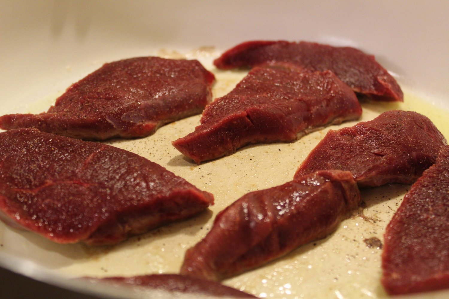 Dark red deer meat sizzling away in the ceramic-coated skillet.